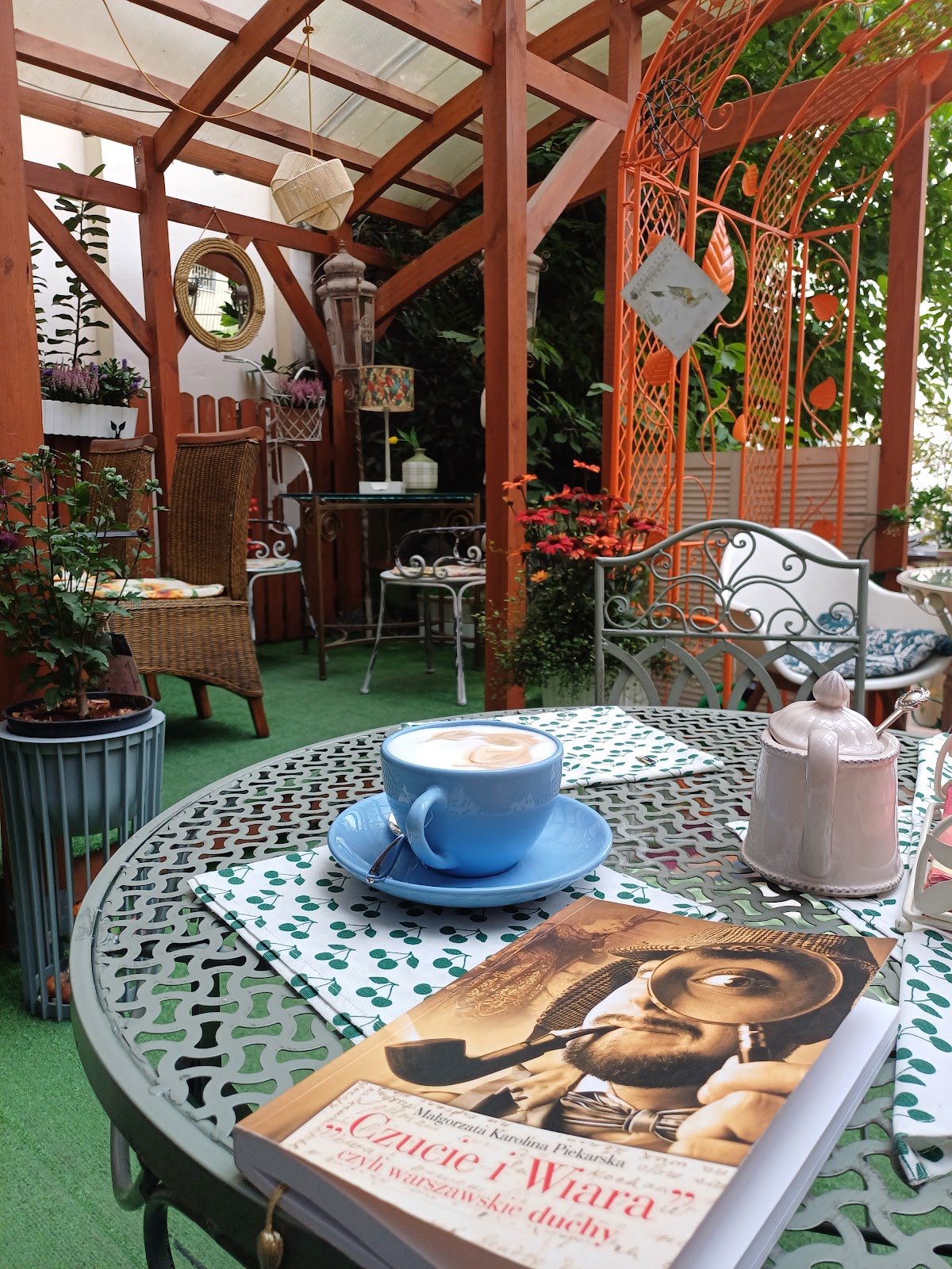 Cappuccino i książka na ogrodowym stole